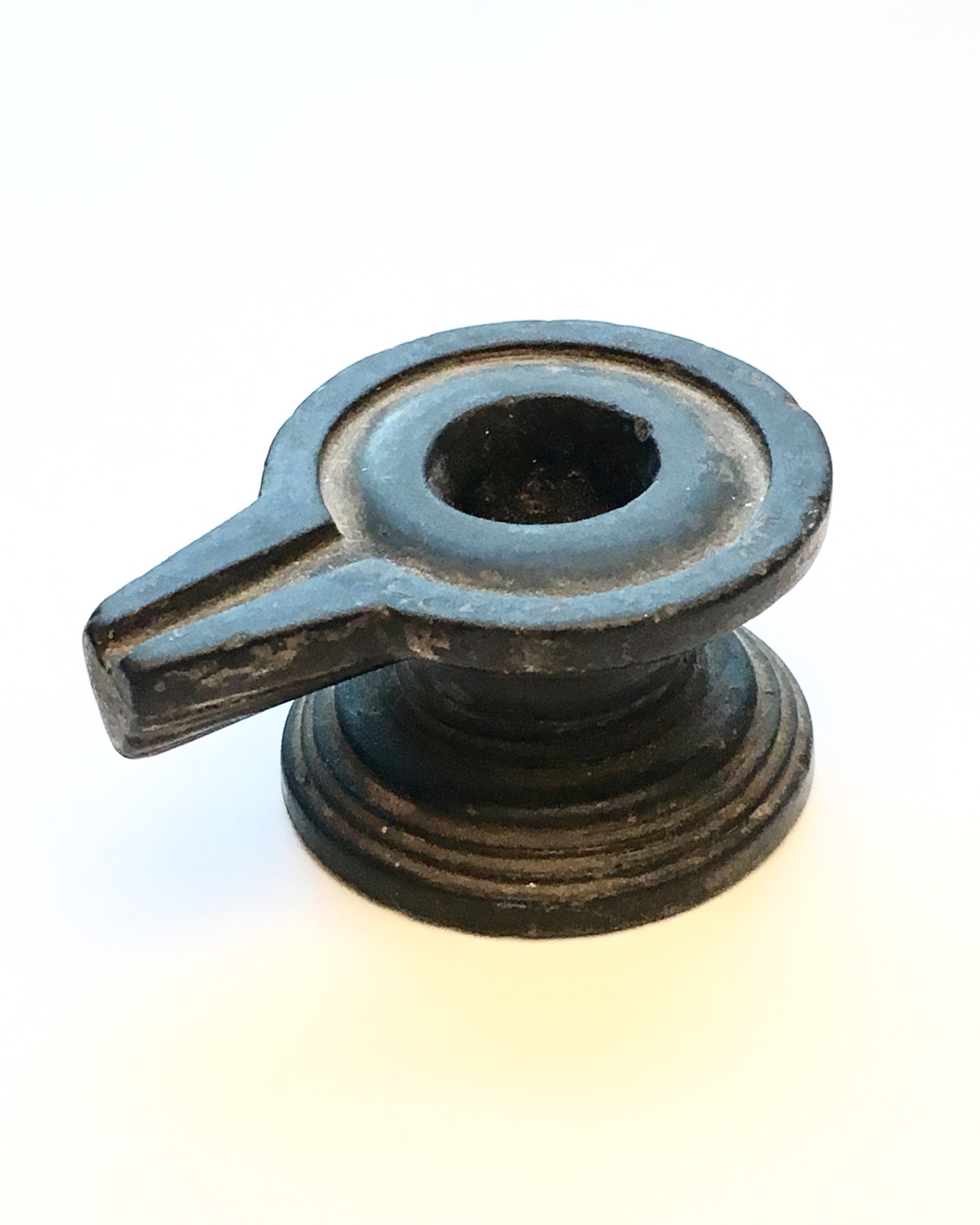 A BLACK CIRCULAR STONE YONI ON A MOULDED FOOT