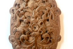 A coconut curved plaque, carved with interweaving scrolling foliage